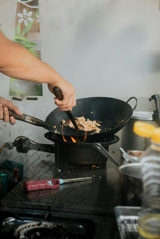 Man stirring fried rice in a wok on a burner